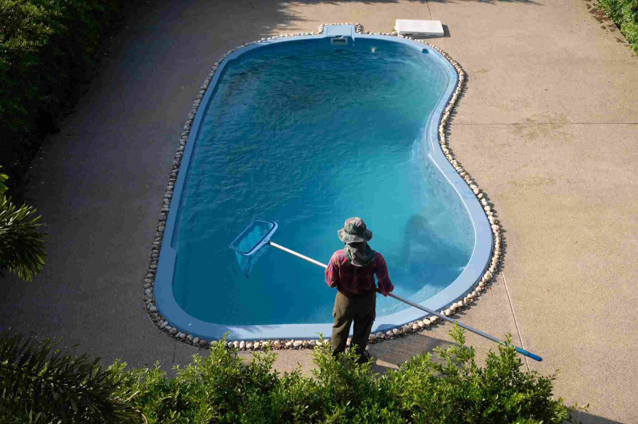 Housekeeping using a long skimmer for removing fallen leaves and debris floating on the surface of the pool.