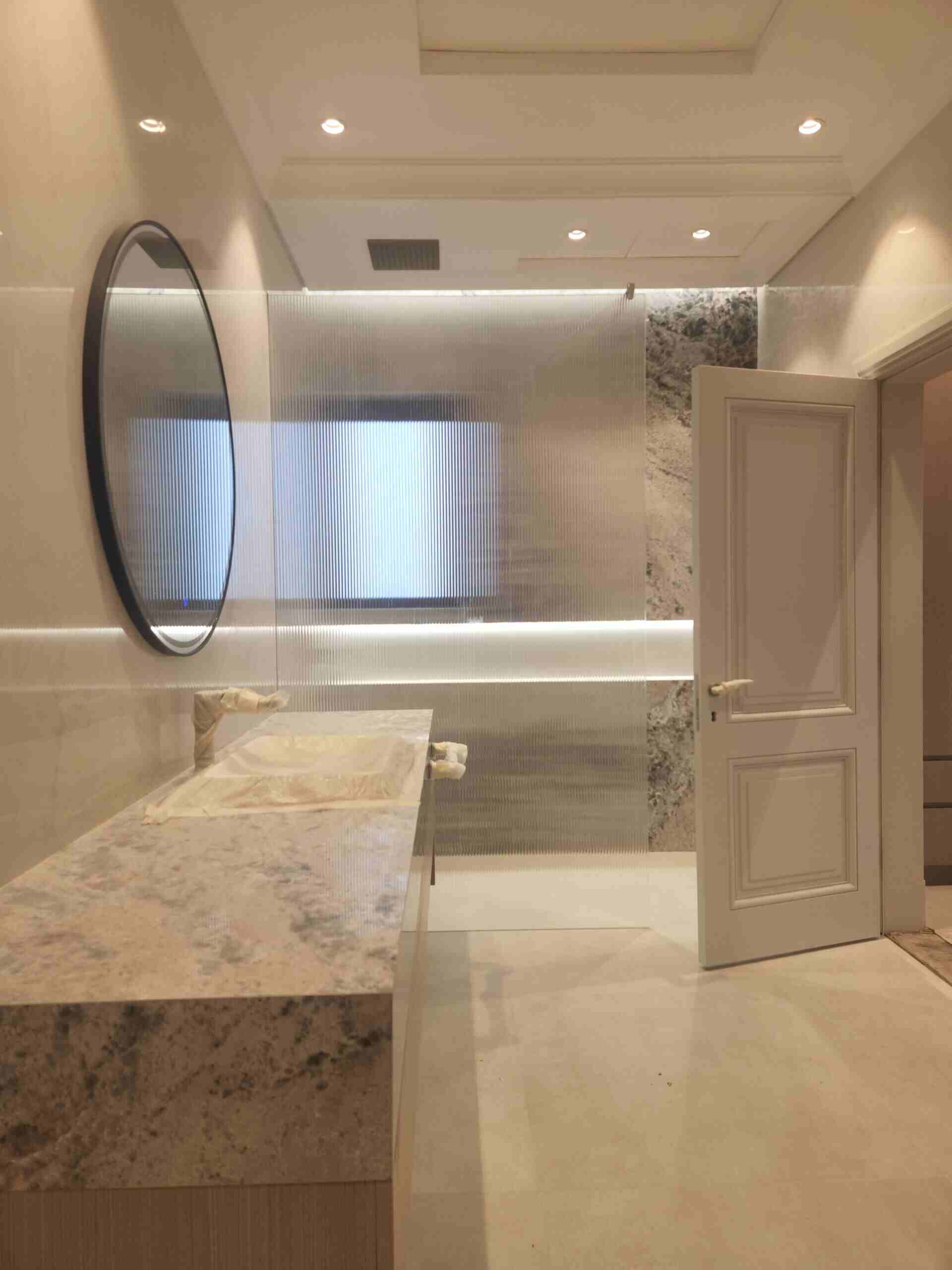 Bathroom with marble countertops, round mirror -